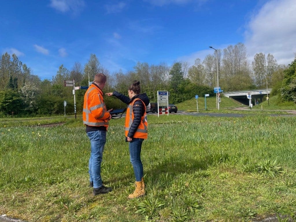 Medewerkers gemeente kijken rond op grasveld.