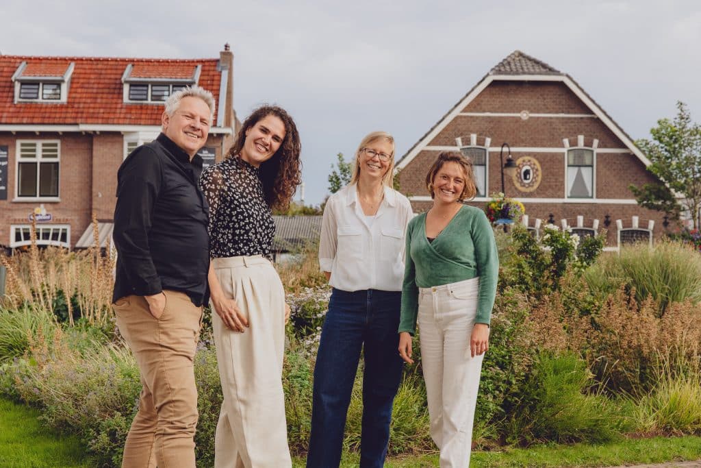4 medewerkers voor grasveld met huizen.