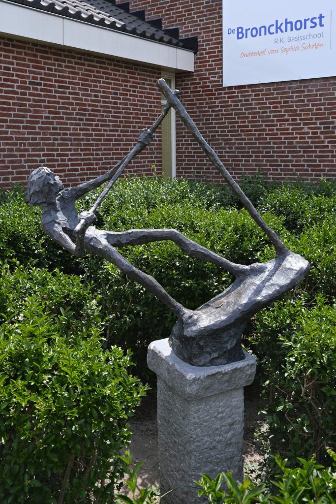 Bronzen beeld van een surfer op surfplank.