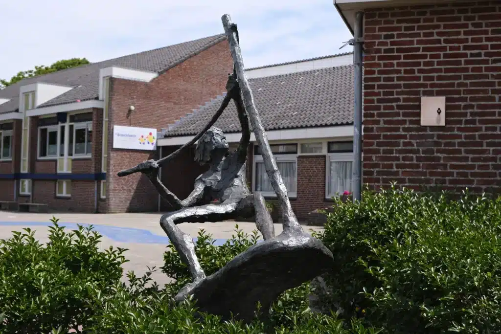 Bronzen beeld van een surfer op surfplank.