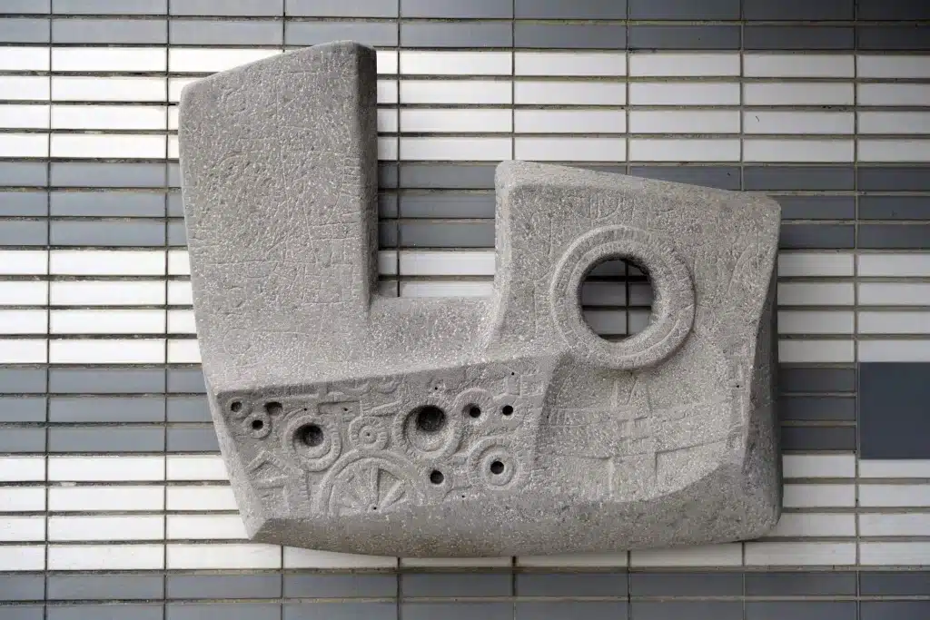 Stenen beeld met gaten op een muur met witte en grijze stenen.