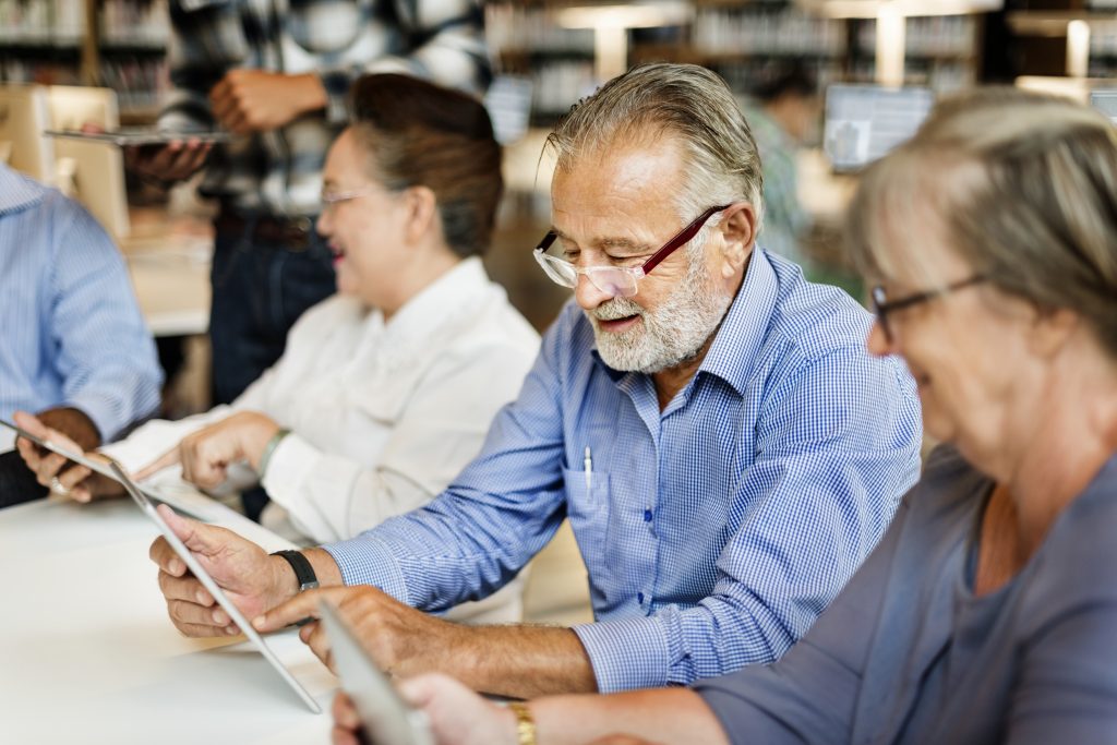 man op tablet in bibliotheek.